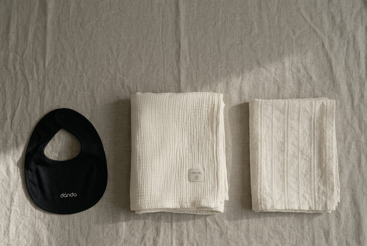 Baby bedding, bibs, and blankets arranged in soft neutral tones.